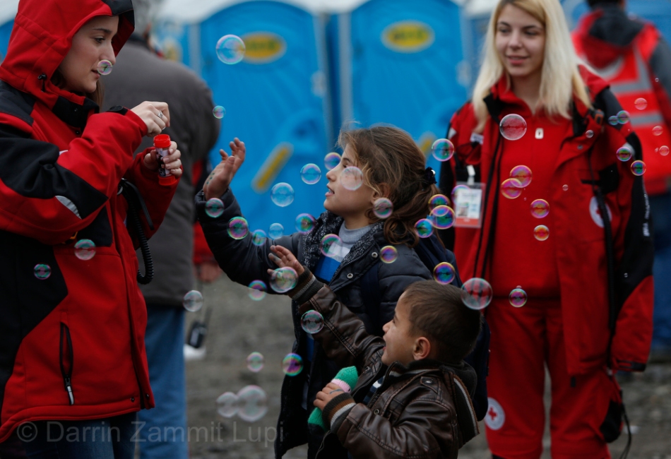 Children play with bubbles blown by volunteers as migrants and refugees are registered by the authorities before continuing their train journey to western Europe at a refugee transit camp in Slavonski Brod